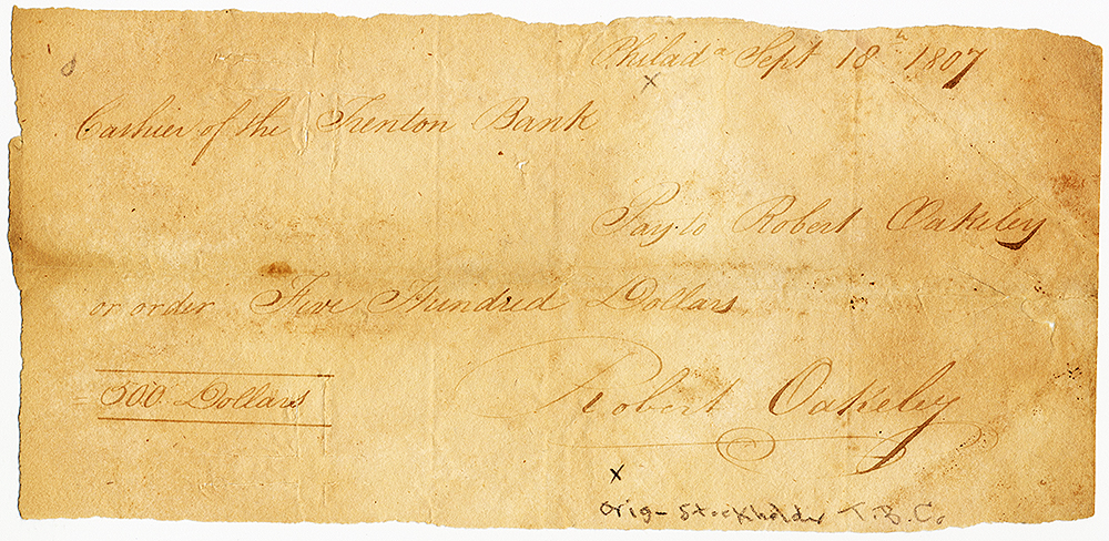 Handwritten check on plain brown paper, dated September, 18, 1807. Script reads Cashier of the Trenton Bank Pay to Robert Oakeley on order five hundred dollars. Signed Robert Oakeley. Paper is cut irregular on top margin. Image is color.