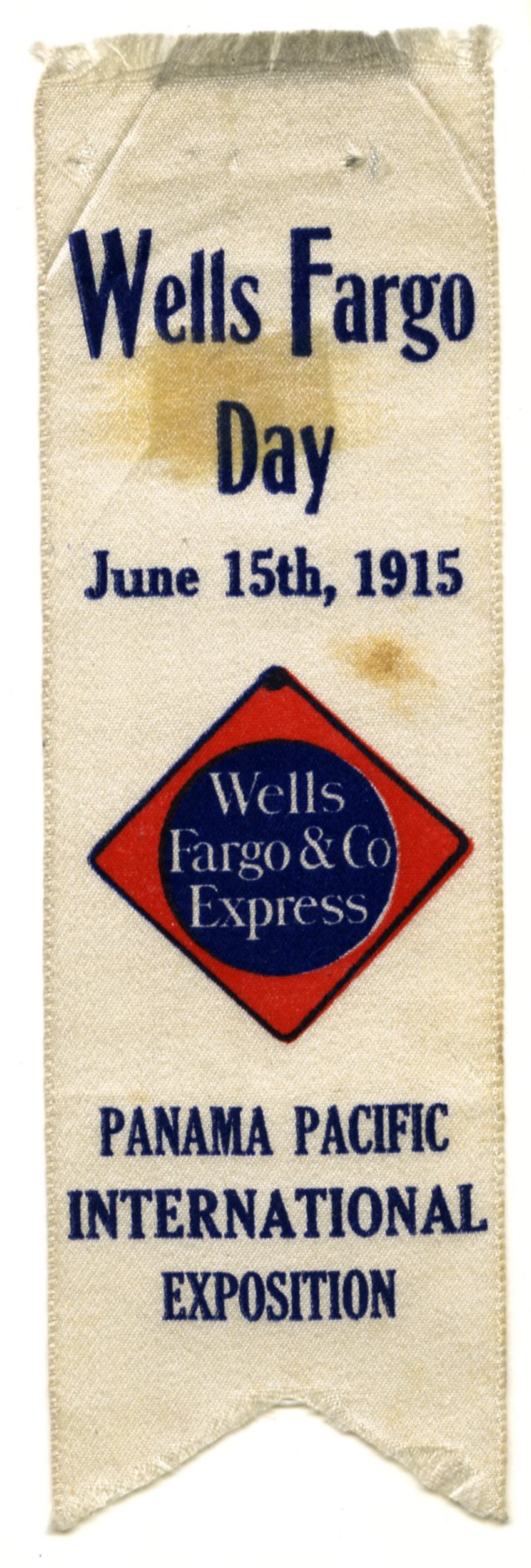A decorative white satin ribbon reads at top Wells Fargo Day June 15, 1915. Also shown is company's red and blue diamond shaped sign at center, and Panama Pacific International Exposition at bottom. Ribbon is rectangular with swallowtail cut at bottom.