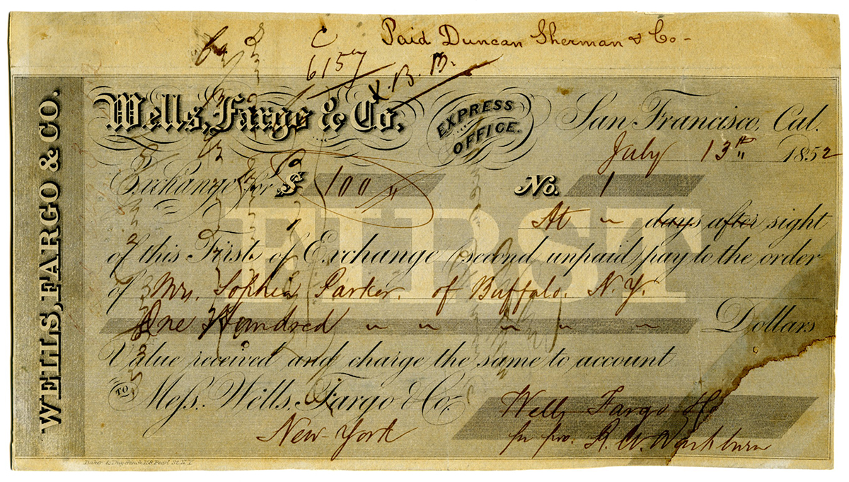 A grey-colored banking exchange document drawn on Wells Fargo & Co. Express Office San Francisco and dated July 13, 1852. Handwritten sum of $100 written in, as is name of Mrs. Sophia Parker of Buffalo, New York as payee. Handwritten notation at top says paid Duncan, Sherman & Co. Signature of R.W. Washburn for Wells Fargo & Co. bottom right. Document is overprinted with large white letters in center reading First. Document is old and shows staining.