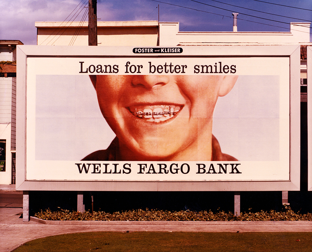 A billboard featuring a young boy smiling showing his white teeth and braces. The billboard includes the words: Loans for better smiles, Wells Fargo Bank.