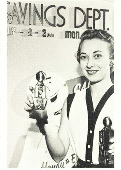 Woman in front of Savings Department sign holds two Northwestern National Bank coin banks with weather ball atop.