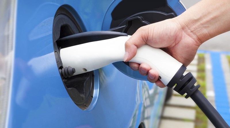 Close up view of a hand plugging in electric car to charge.