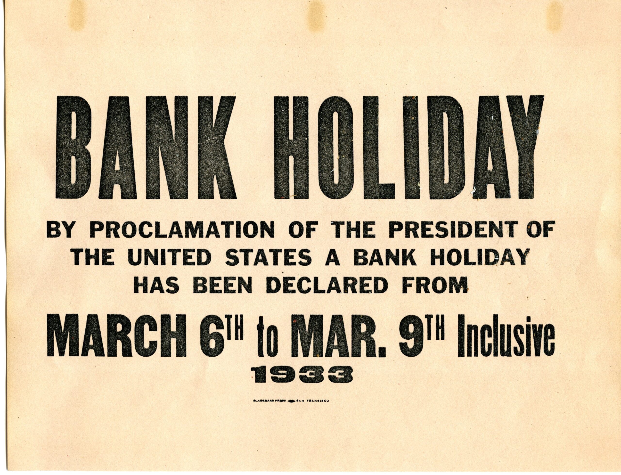 A yellow sign hung on branches from 1933 that reads: Bank Holiday by proclamation of the President of the United States a bank holiday has been declared from March 6th to March 9th Inclusive 1933. Image link will enlarge image.