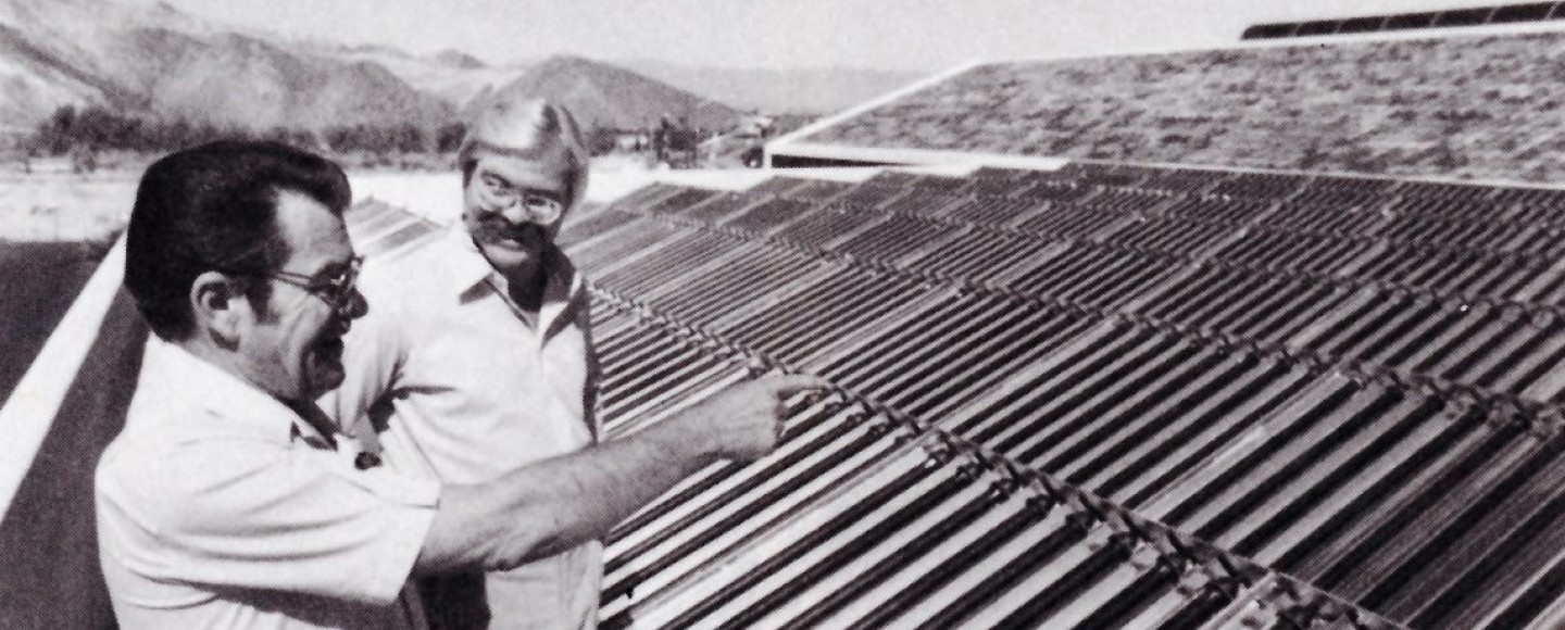 Two men looking at solar panels in the desert.