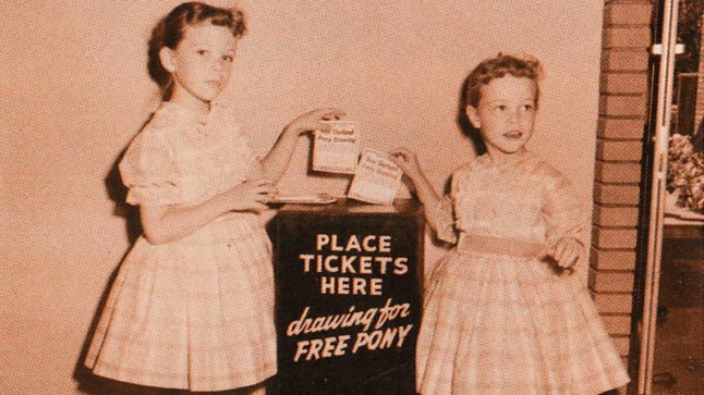 Two girls in identical dresses place their tickets into a ballet box that reads: Place tickets here drawing for free pony.