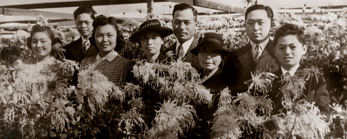 Eight members of the Nakano family pose together inside their flower nursery in 1939. Historic black and white picture.