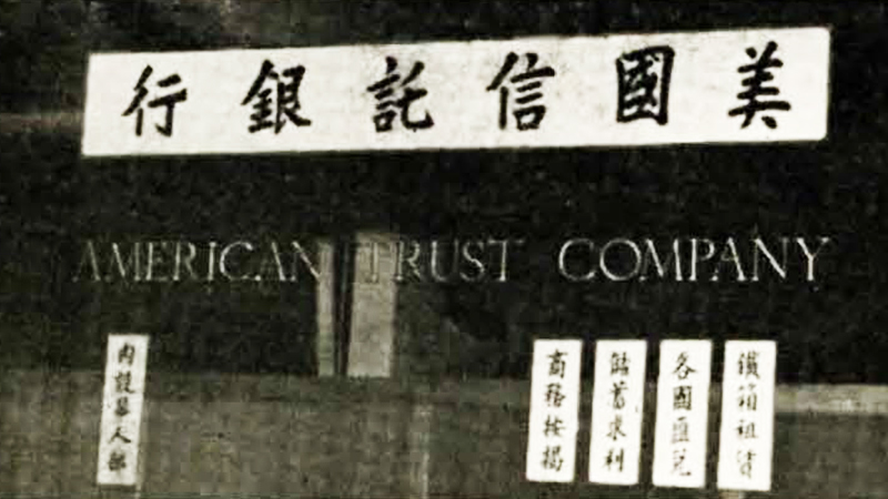A window of a branch that reads American Trust Company in English and also America, Trust, Bank in Chinese.