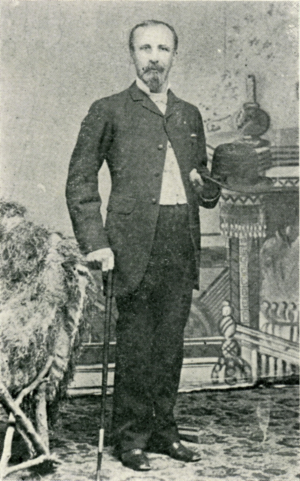 A black and white photo of a man posing in a suit and with a cane. Image link will enlarge image.
