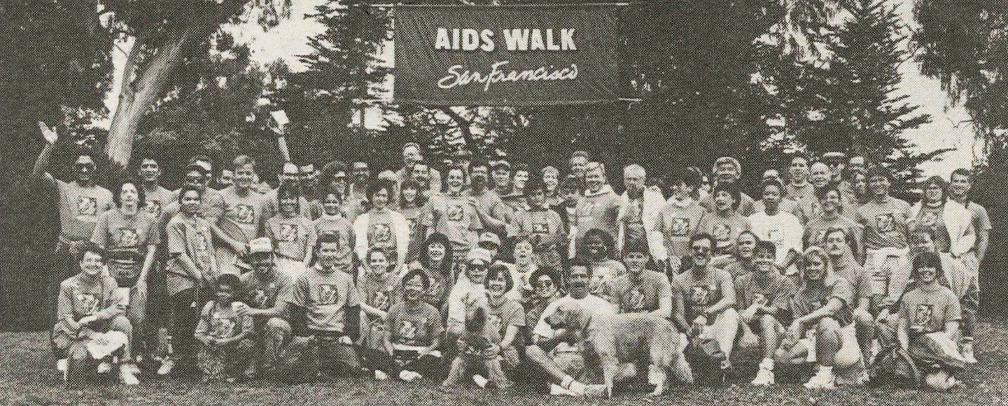 A 1991 photo of a large crowd of people gathered outside under a banner that reads AIDS Walk San Francisco.